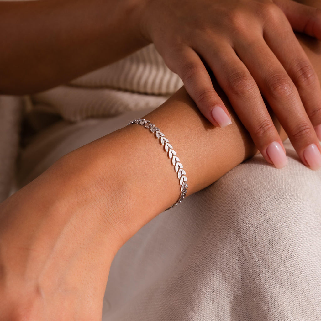 Close-up of model wearing a white gold leaf link chain bracelet.