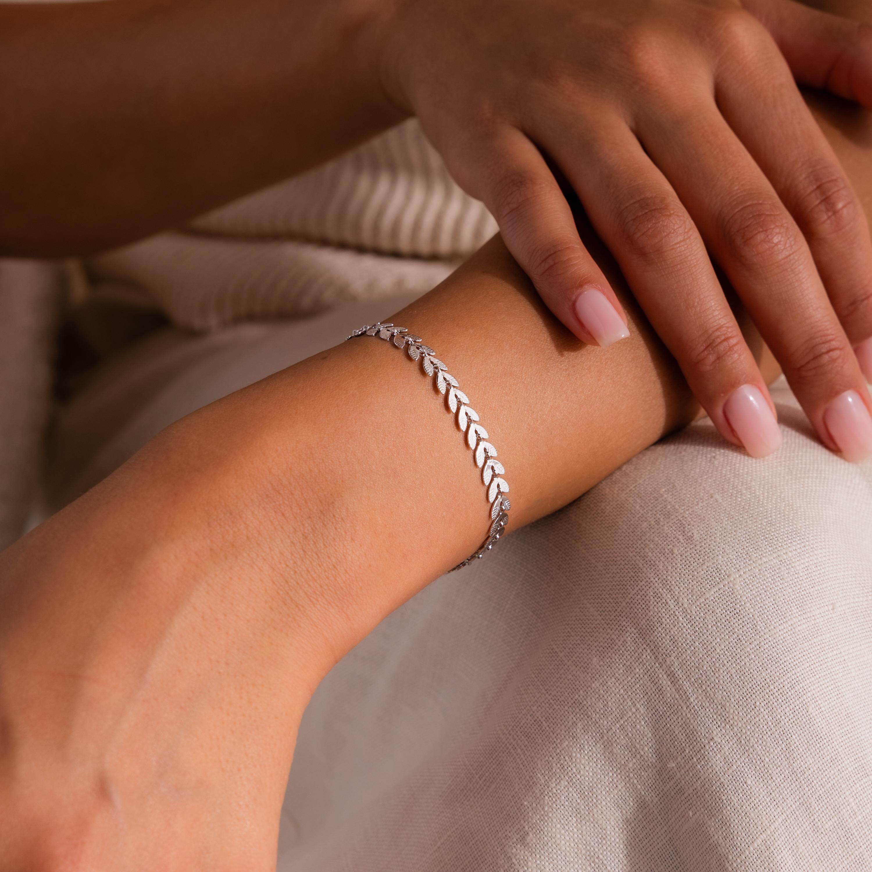 Close-up of model wearing a white gold leaf link chain bracelet.