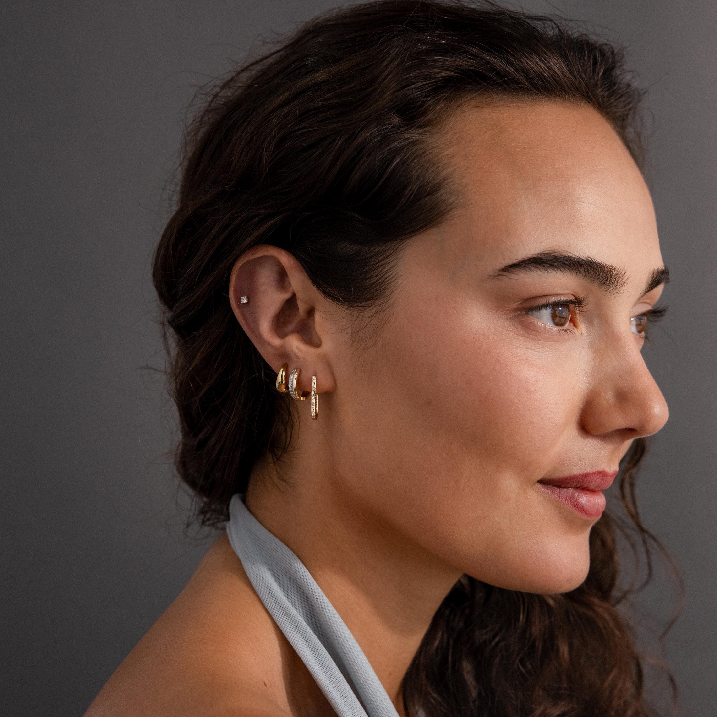 Woman with long dark hair wearing Dainty Pave Link Earrings—minimalist gold hoops and a stud, possibly featuring cubic zirconia accents—looking to the right with a slight smile.