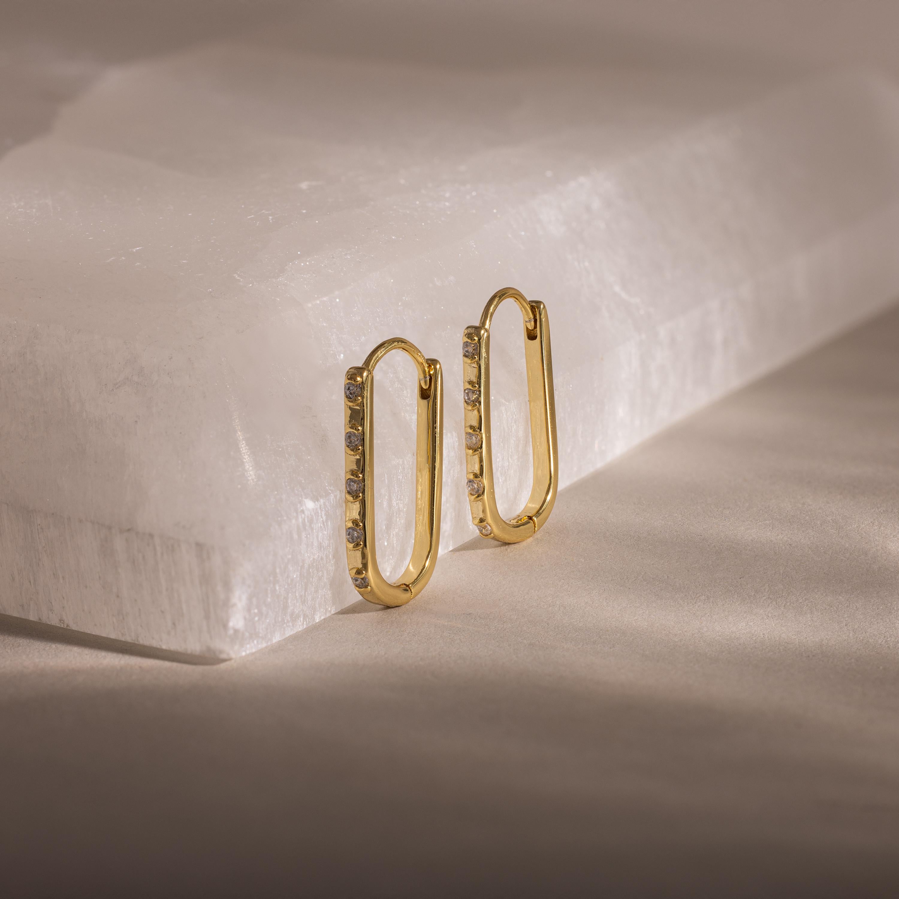 Dainty Pave Link Earrings—gold rectangular hoops with cubic zirconia, shown on a white stone surface in soft light. These minimalist earrings add subtle sparkle to any look.