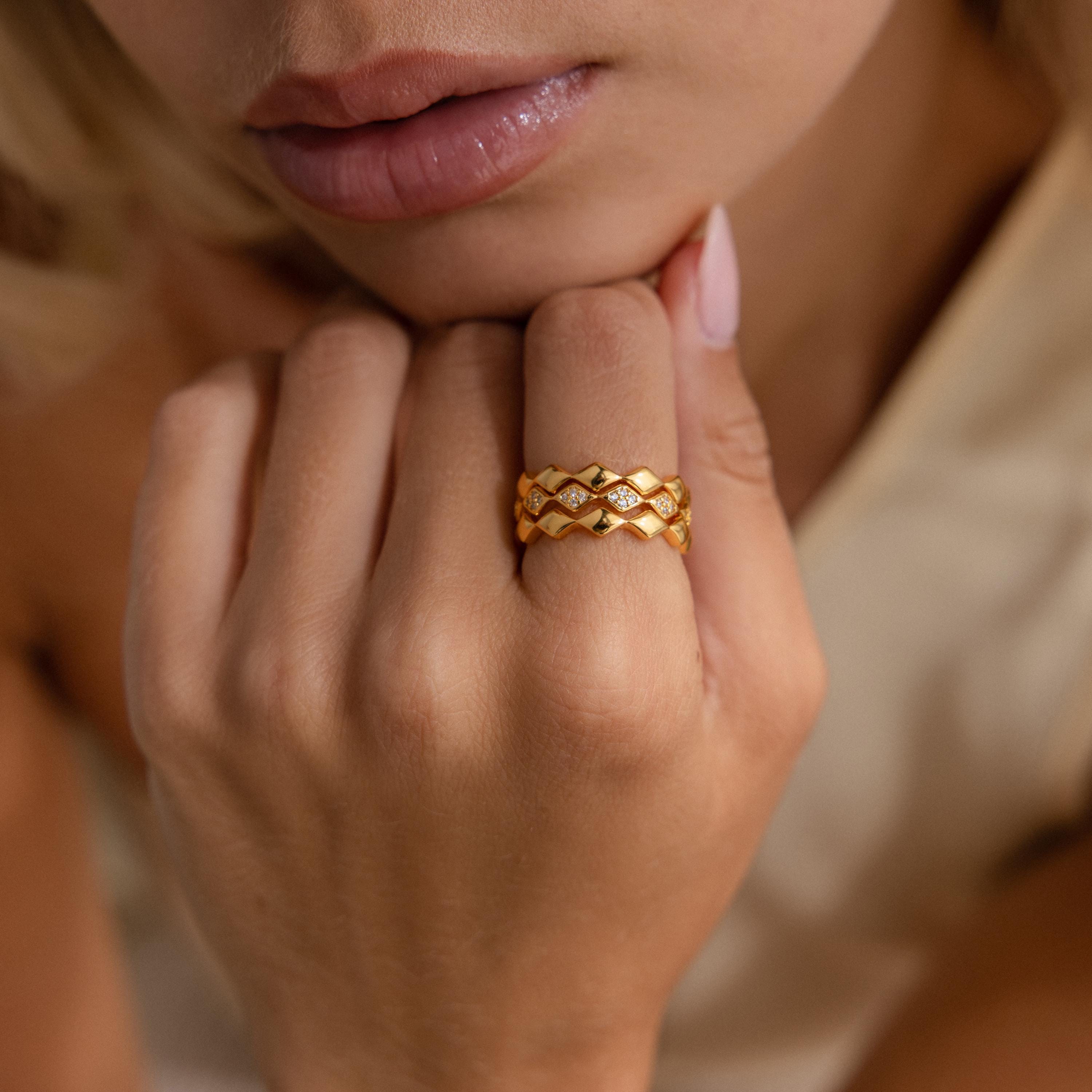Close-up of model wearing set of 3 eternity curve rings in gold with quilted detailing and diamond accents, styled together for a bold and elegant statement look.