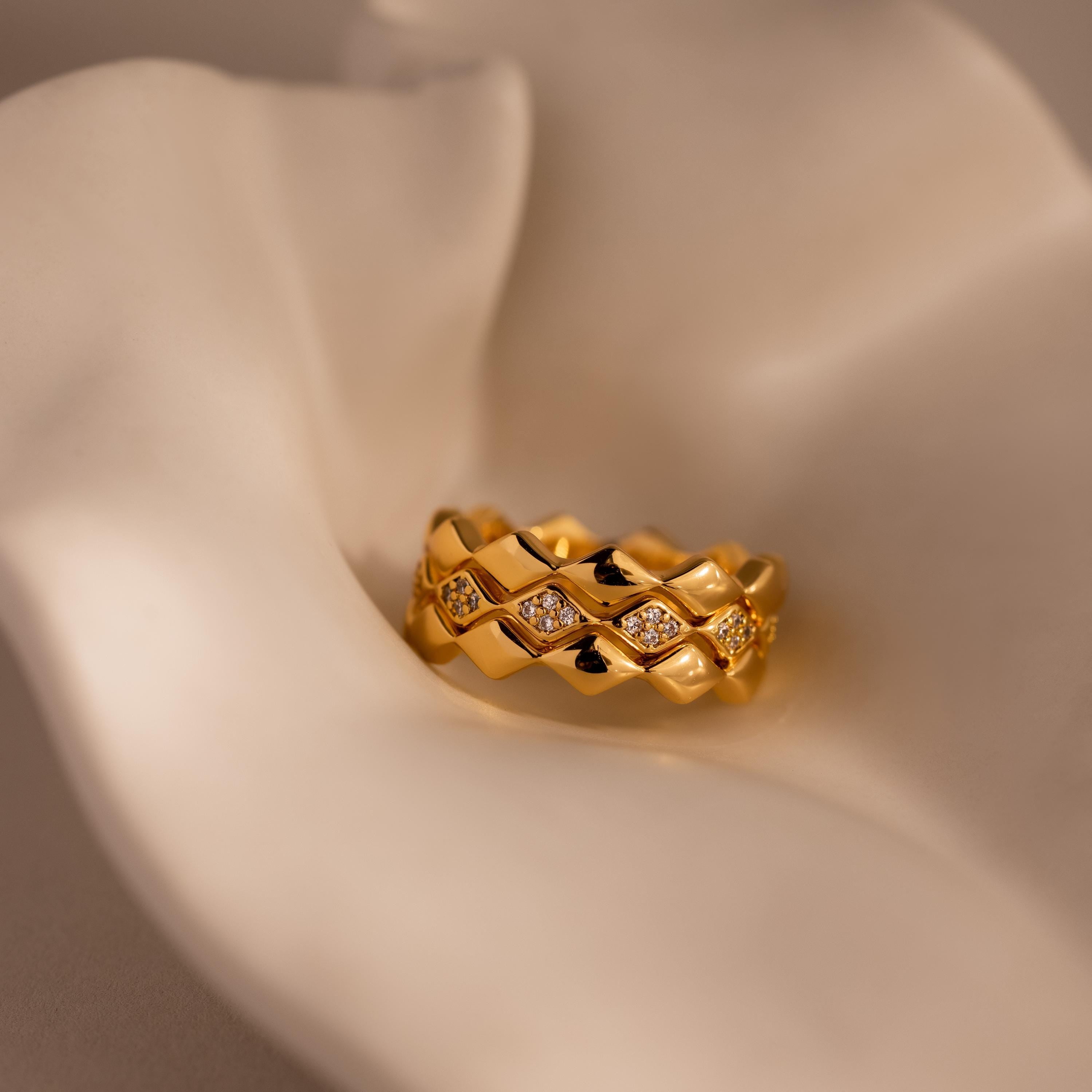 Set of 3 eternity curve rings in gold with quilted detailing and diamond accents, displayed on soft cream fabric for a refined and luxurious jewelry presentation.