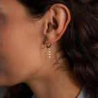 Close-up of a woman's ear wearing Duo Mirror Chain Huggies in 18K Gold—sleek hoops featuring modern layered details and delicate mirror-cut bead chains.