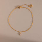 Gold chain bracelet featuring a small crystal cross charm and adjustable clasp with heart detail, a delicate and meaningful jewelry piece perfect for layering or everyday wear.