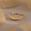The Organic Diamond Curve Ring features a gold band with three sparkling marquise diamonds set on one side, showcased against a neutral background.
