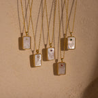 Five elegant gold chain necklaces with rectangular pendants, each adorned with engraved designs, small colored gems, and pearls—a stylish Pearl Zodiac Birthstone Necklace perfect for personalized jewelry lovers.