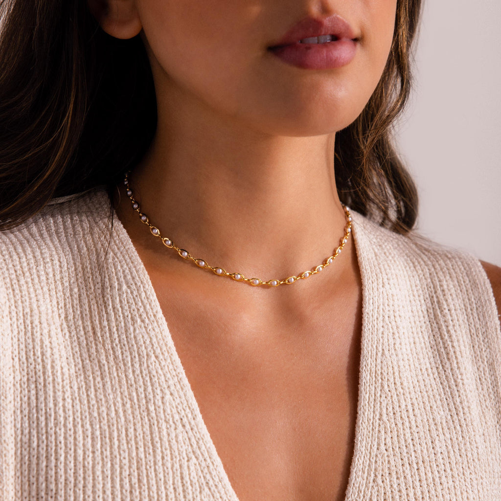 Gold pearl chain choker necklace with white pearls set in oval gold links, shown on model for a modern and elegant look.
