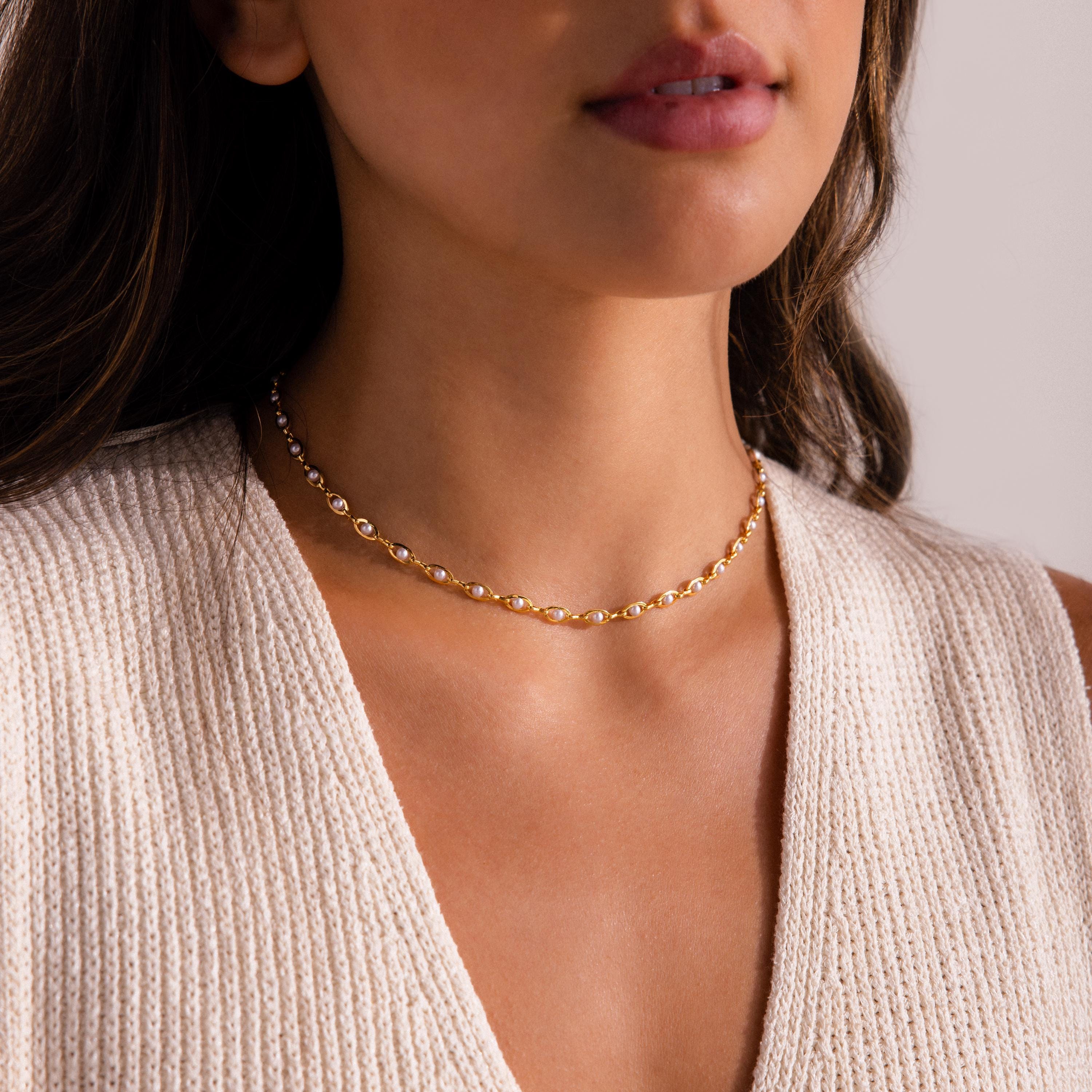 Gold pearl chain choker necklace with white pearls set in oval gold links, shown on model for a modern and elegant look.