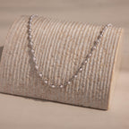 Silver pearl chain necklace with white pearls set in oval silver links, displayed on textured stand for an elegant, modern presentation.