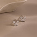 Silver Starlight Bow stud earrings with baguette-cut clear stones arranged in a delicate bow design, displayed on a soft neutral background for an elegant presentation.