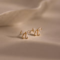 Gold Starlight Bow stud earrings with baguette cut clear stones arranged in a delicate bow design, displayed on a soft neutral background for an elegant look.