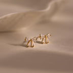 Gold Starlight Bow stud earrings with baguette cut clear stones arranged in a delicate bow design, displayed on a soft neutral background for an elegant look.