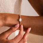 Woman wearing the Beaded Pearl Bracelet in gold, featuring faceted metallic beads with a single natural white pearl centerpiece, styled on the wrist for an elegant and timeless look.