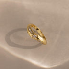 Radiant Facet Ring in polished gold featuring diamond shaped CZ stones with pave set side stones, displayed on a softly lit neutral surface with shadow detail.