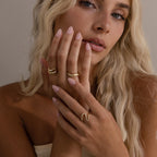 Woman wearing multiple gold rings including the Radiant Facet Ring with diamond shaped and pave accents, styled with soft waves and natural makeup.