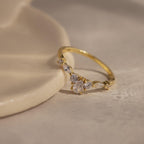 Radiant Tear Ring in polished gold featuring a pear cut diamond center with round and marquise side stones, displayed on a smooth neutral surface.