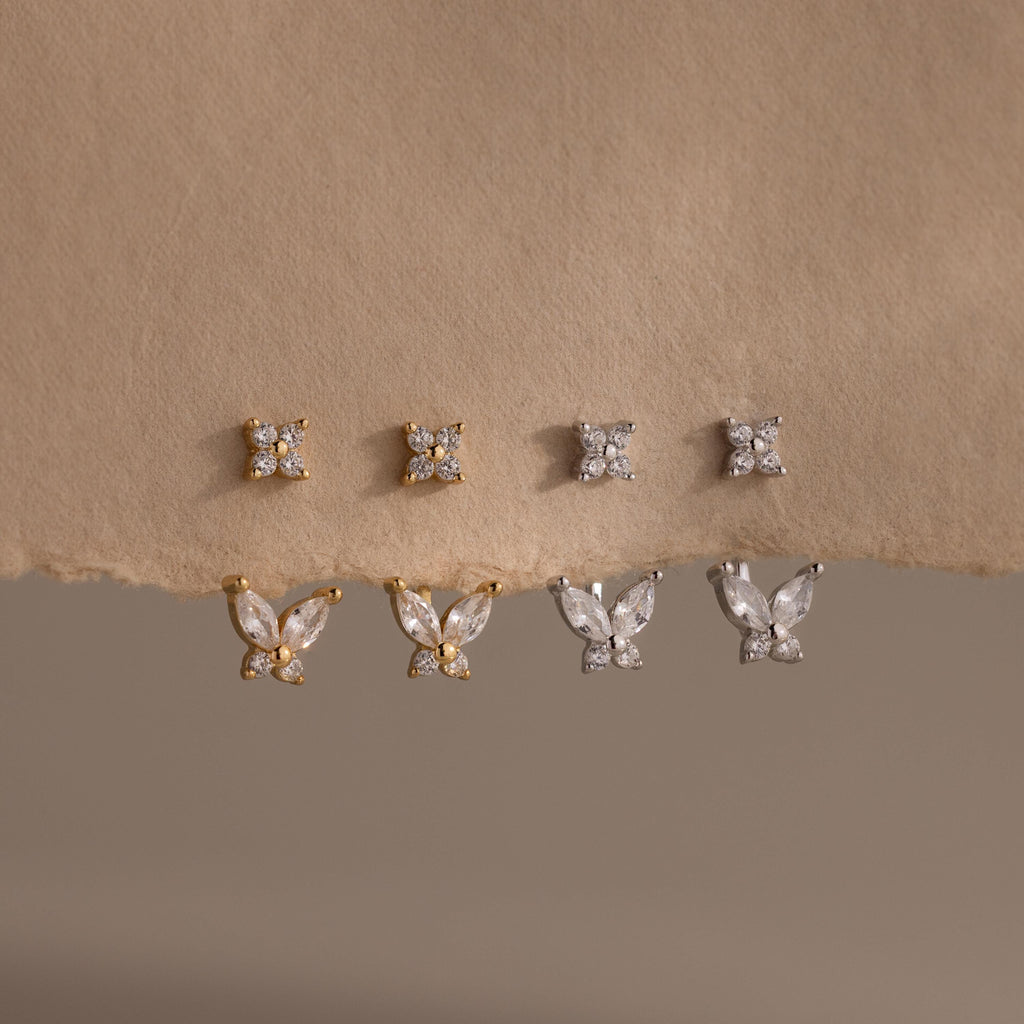 Pairs of gold and silver Butterfly Ear Jackets hang from a paper backdrop