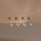 Pairs of gold and silver Butterfly Ear Jackets hang from a paper backdrop