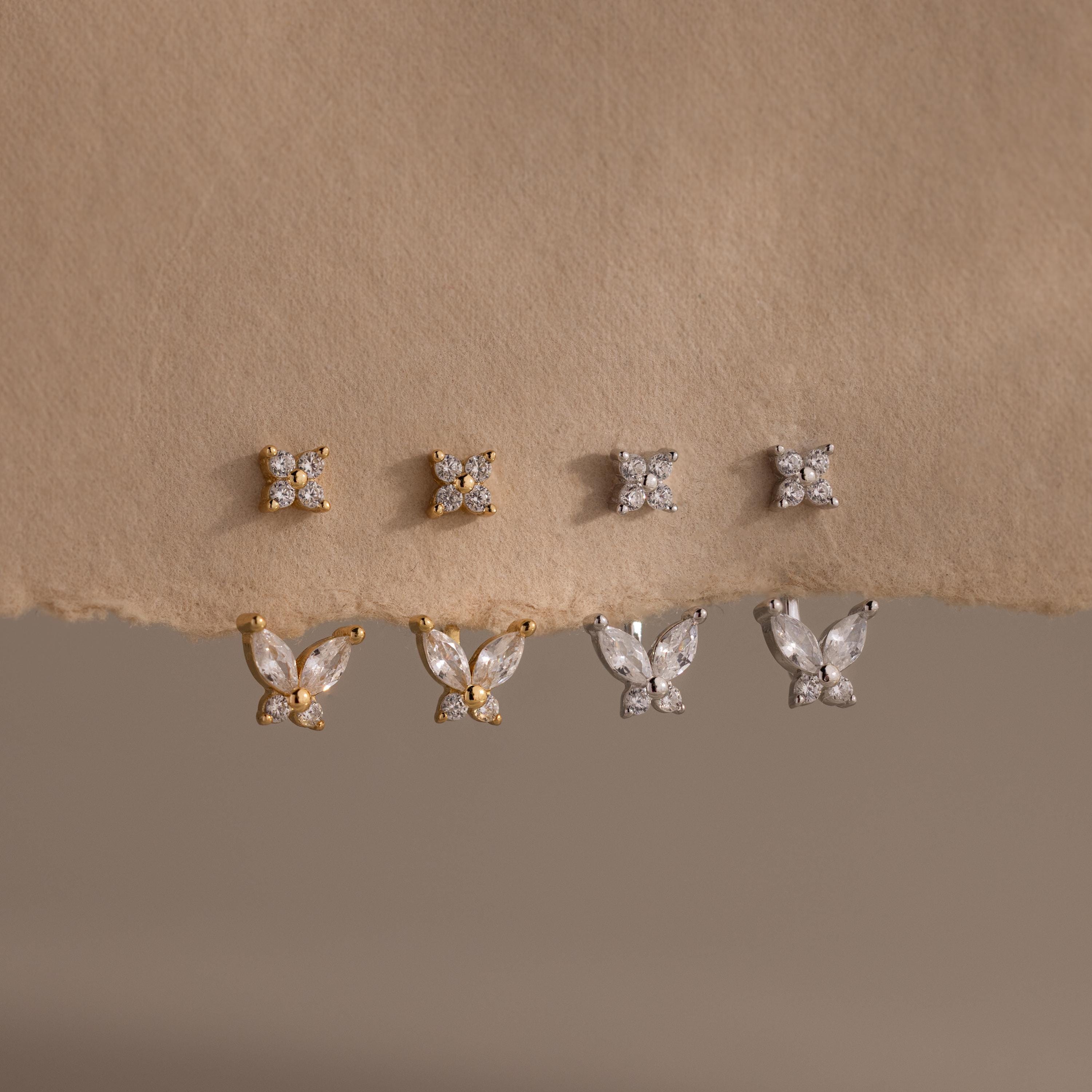 Pairs of gold and silver Butterfly Ear Jackets hang from a paper backdrop