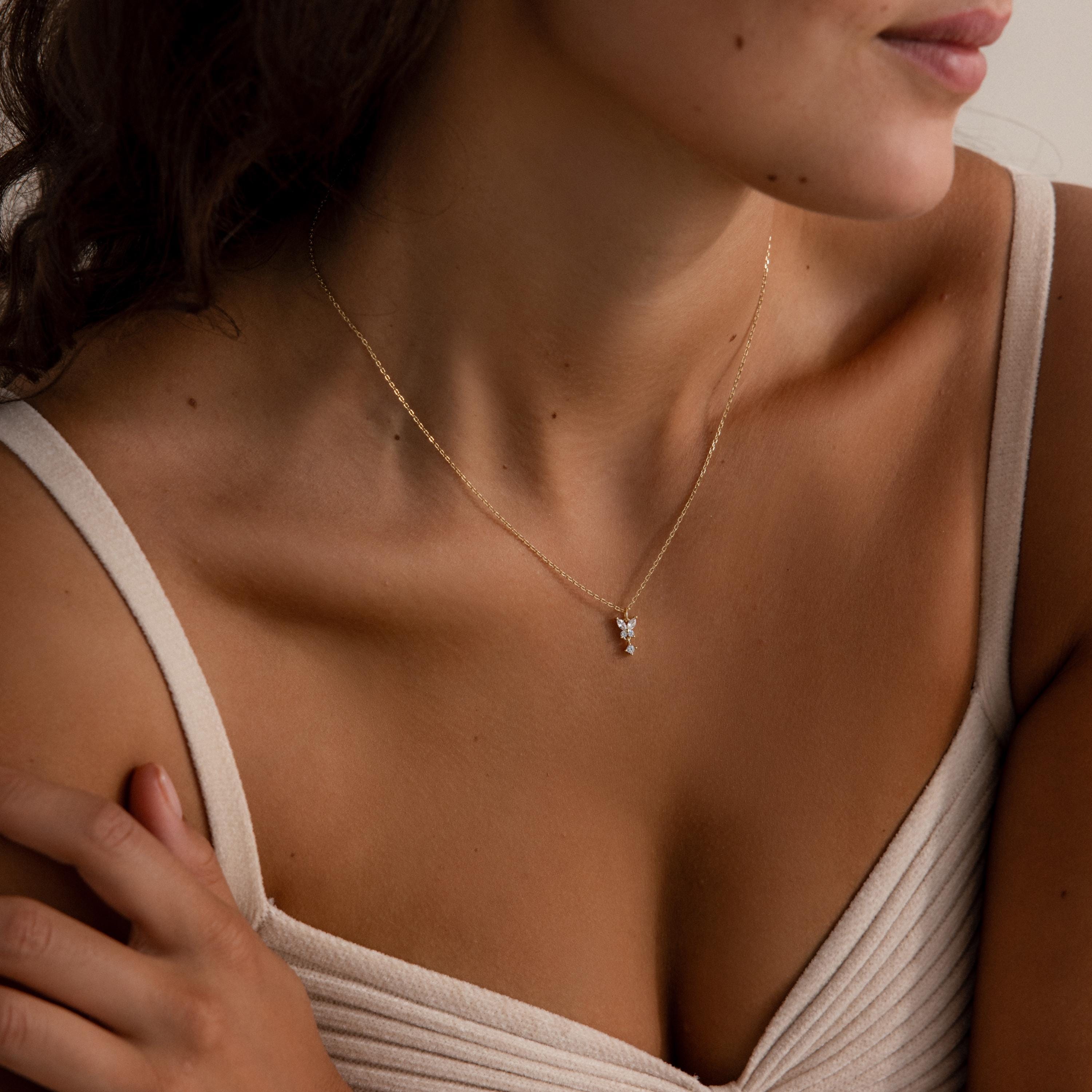 Woman shown from the shoulders up wears a cream top and the Butterfly Drop Necklace in 18K Gold, featuring a delicate, nature-inspired butterfly pendant.