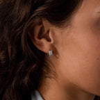 Close-up of a womans ear wearing Ribbed Pave Huggies in Sterling Silver—small hoops with multiple rows of sparkling cubic zirconia stones.