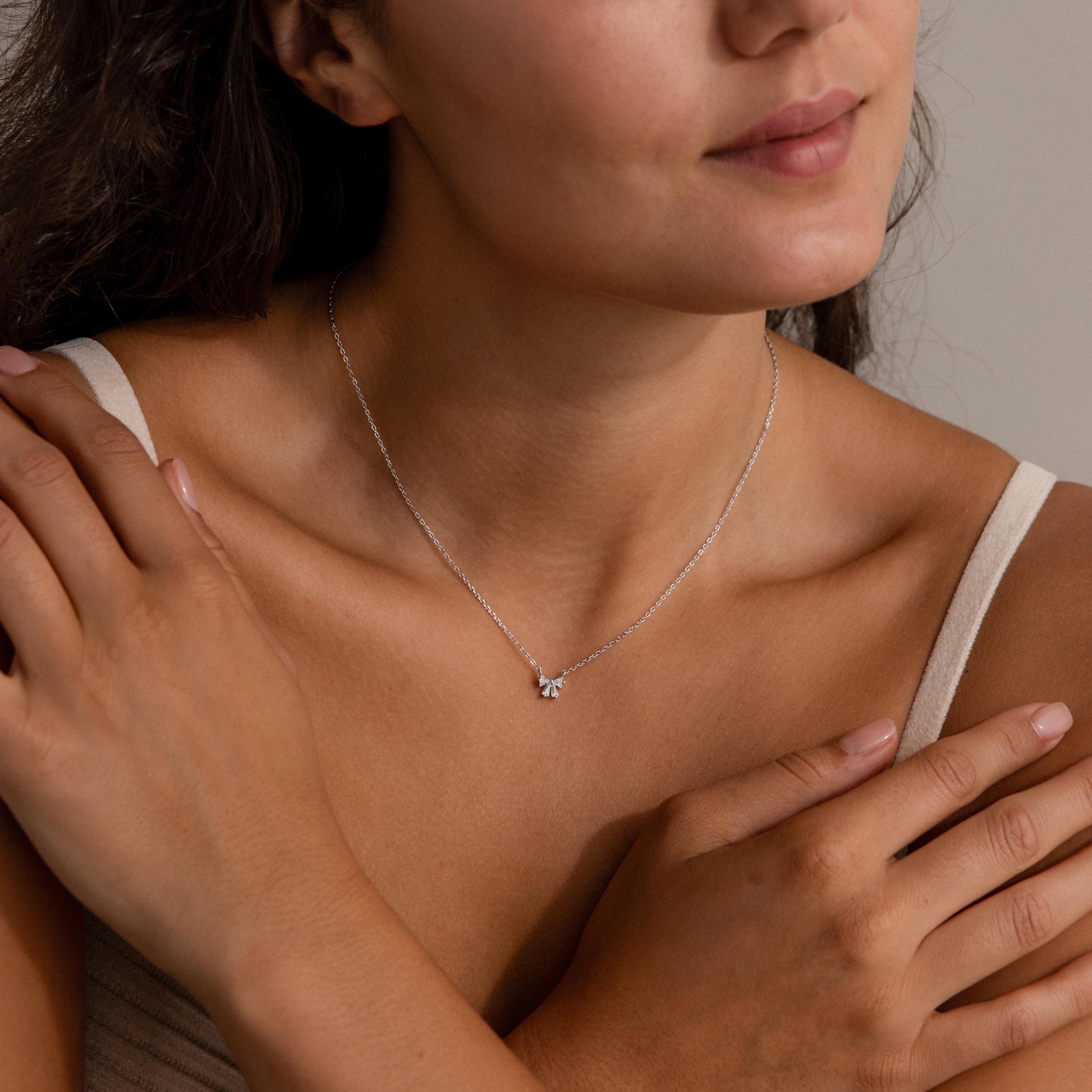 Woman wearing a Diamond Bow Necklace in Sterling Silver, featuring a small bow pendant, hands gently touching her shoulders.