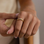 A close-up of a hand wearing the Zen Diamond Curve Ring, featuring a subtle diamond accent, with natural nails against a neutral background.