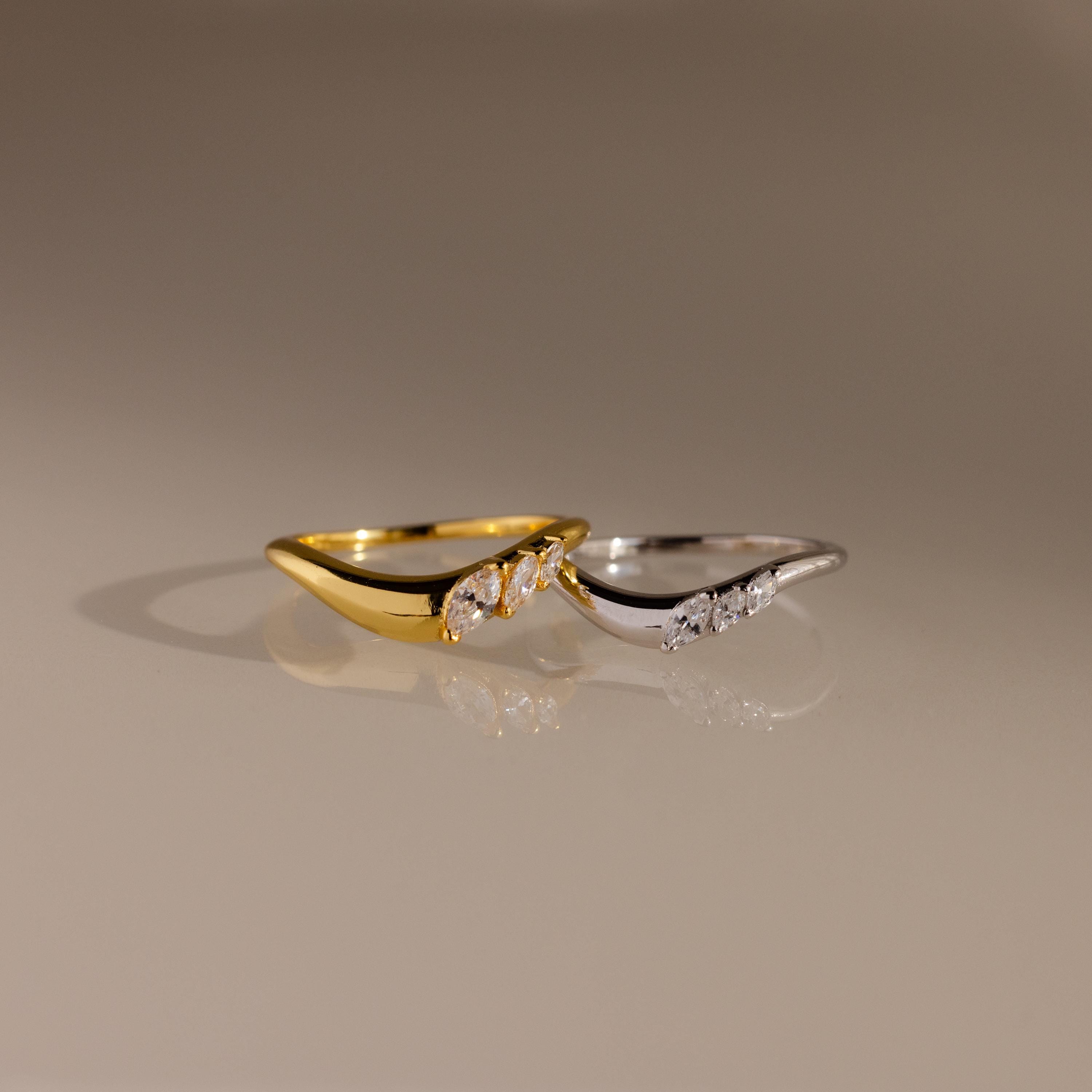 Gold and silver curve rings with marquise cut stones, designed in a sleek wavy silhouette for stacking or standalone wear.