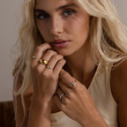 Gold and silver curve rings with marquise and round cut stones stacked together, styled on soft textured fabric for an elegant display.