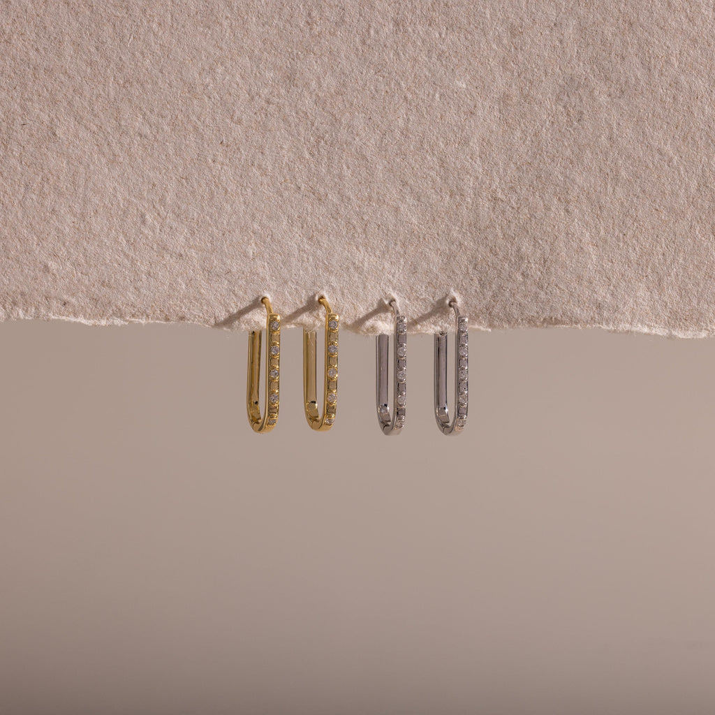 Two pairs of Dainty Pave Link Earrings—one gold, one silver—are displayed on textured beige paper, creating a minimalist look perfect for effortless everyday style.