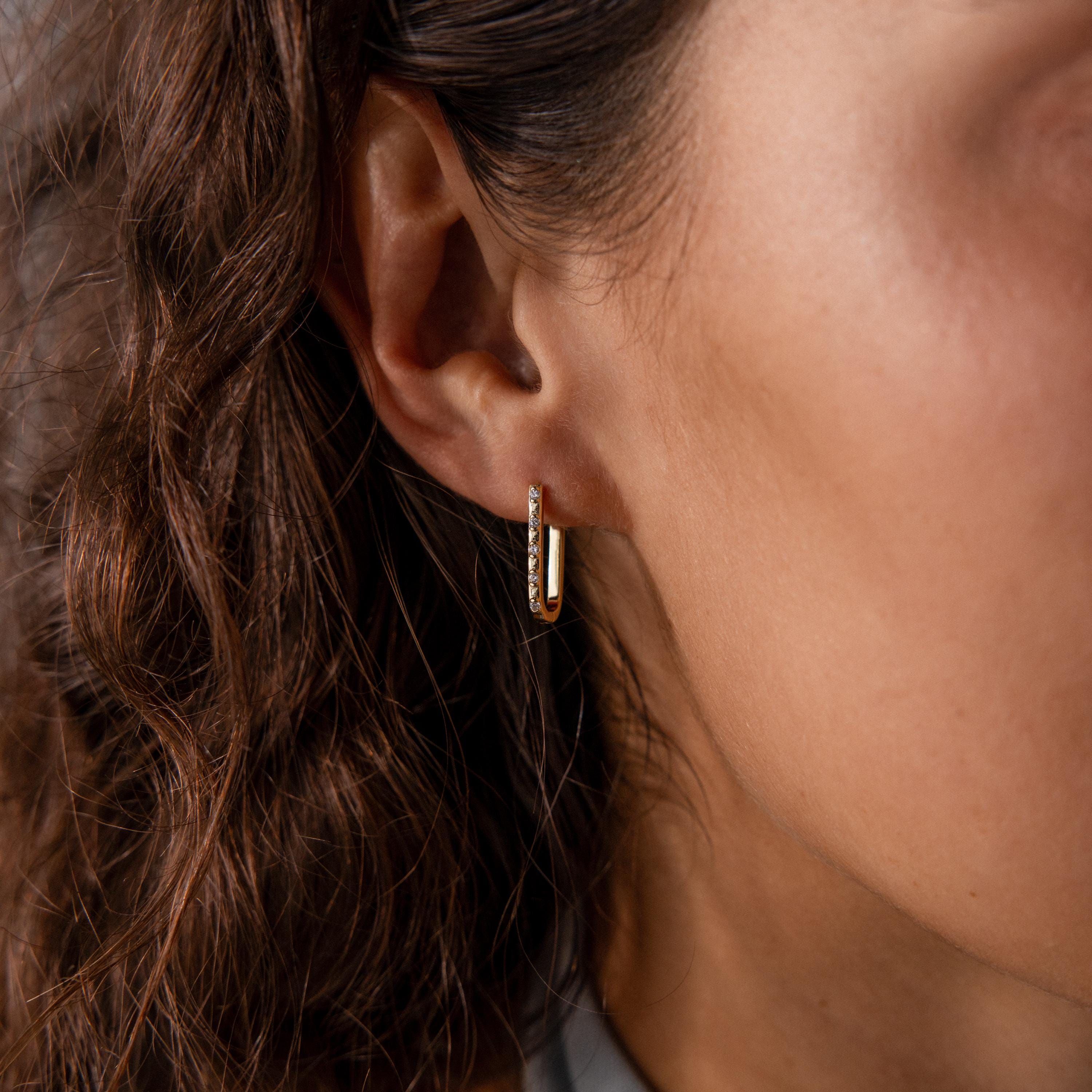 Close-up of a womans ear wearing the Dainty Pave Link Earrings in 18K Gold, featuring minimalist hoops with a row of sparkling cubic zirconia stones.
