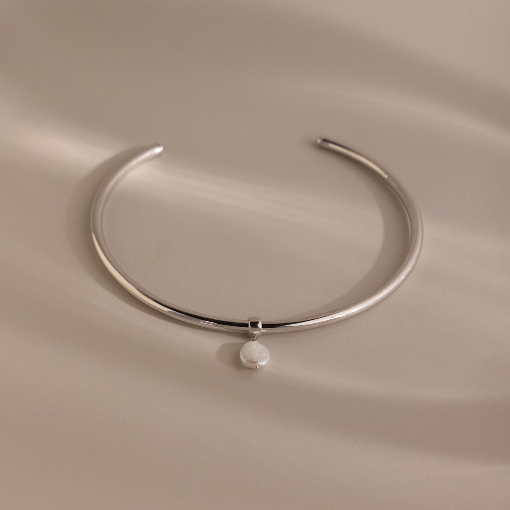 Pearl Cuff Choker Necklace in White Gold featuring a minimalist design with a single round white pearl pendant, displayed on a neutral background.