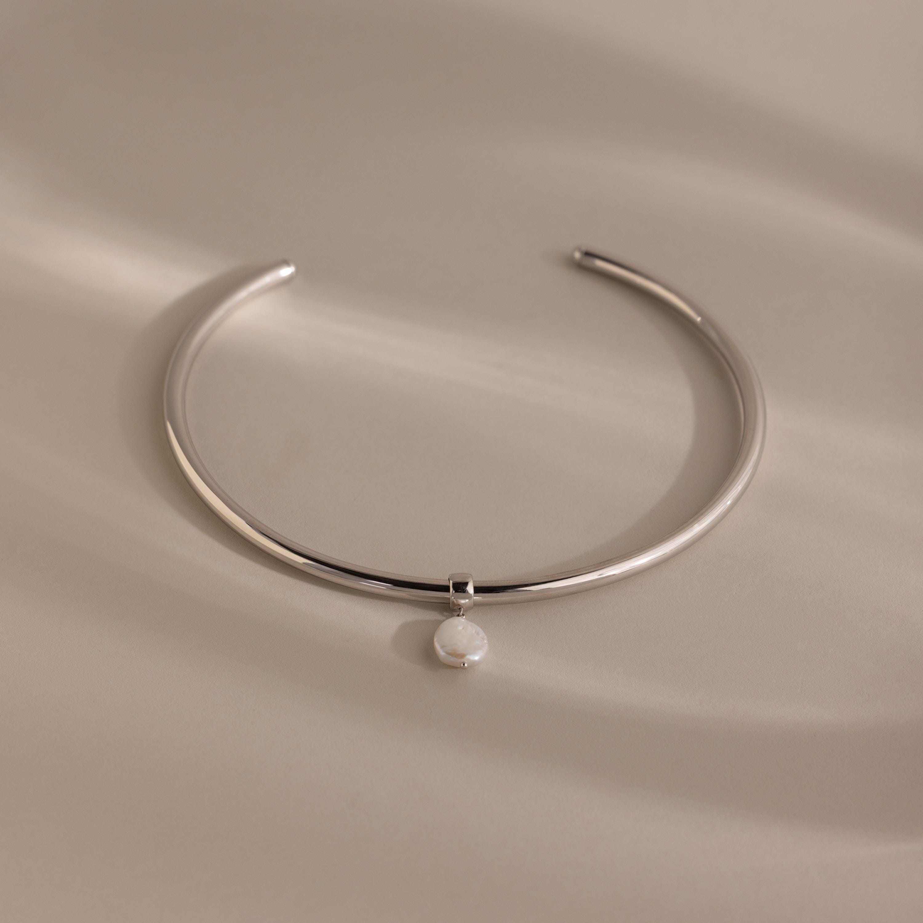 Pearl Cuff Choker Necklace in White Gold featuring a minimalist design with a single round white pearl pendant, displayed on a neutral background.