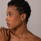 Woman with short curly hair looking left, wearing Royal Blue Checkered Huggies and touching her shoulder.