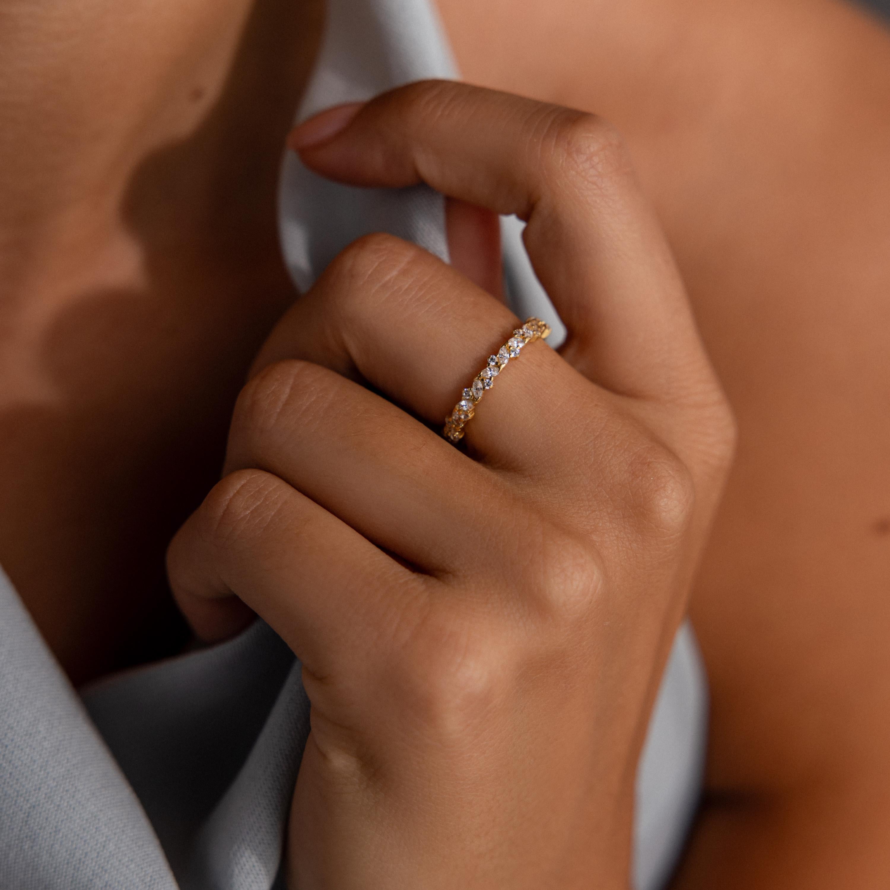A hand adorned with the Diamond Cluster Eternity Ring softly touches a chin, with a gentle, light fabric background.