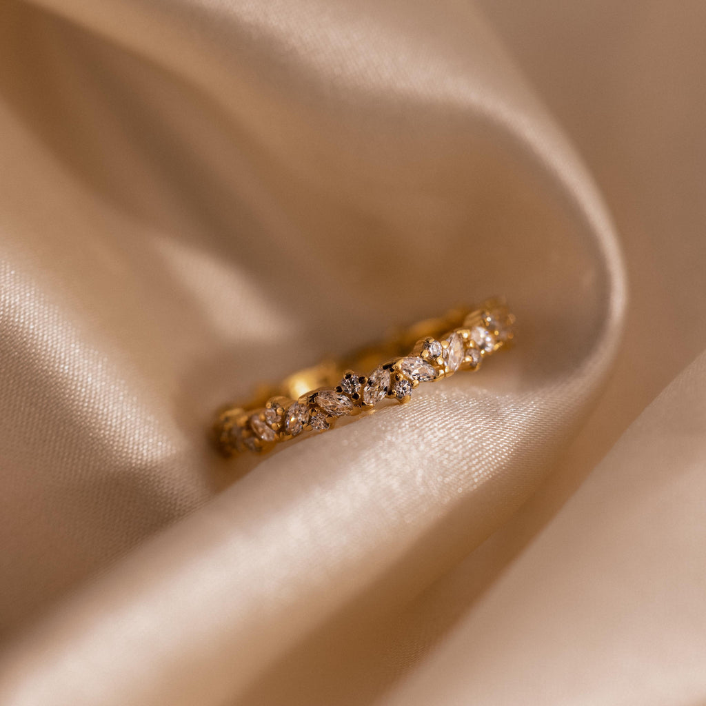 The Diamond Cluster Eternity Ring is displayed on soft, beige satin fabric.