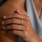 A hand with light pink nails wearing the Diamond Cluster Eternity Ring in gold rests on a shoulder in a soft gray top.