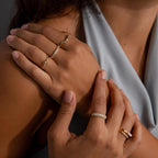 A woman with manicured nails showcases a Diamond Cluster Eternity Ring, her hands elegantly resting on her shoulder.