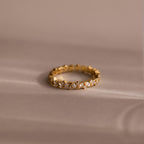 The Diamond Cluster Eternity Ring rests on a soft beige surface, showcasing its brilliant design.