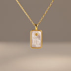 The Pearl Zodiac Birthstone Necklace features a gold rectangular pendant with the Virgo zodiac symbol on a pearly background—a stunning and unique piece of personalized jewelry.