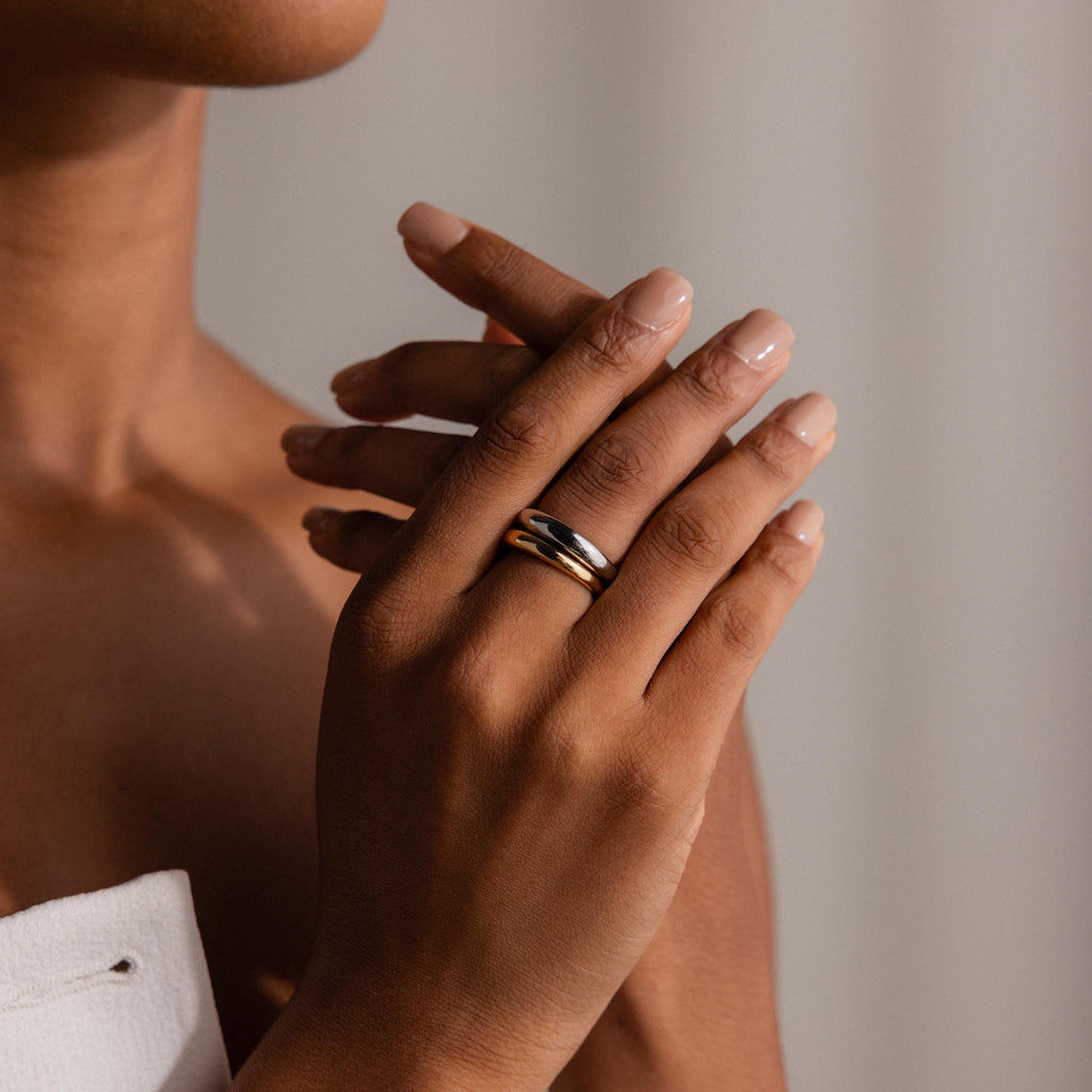 A person with manicured nails wears the Mixed Metal Dome Ring Set on their finger, hands gently clasped together.