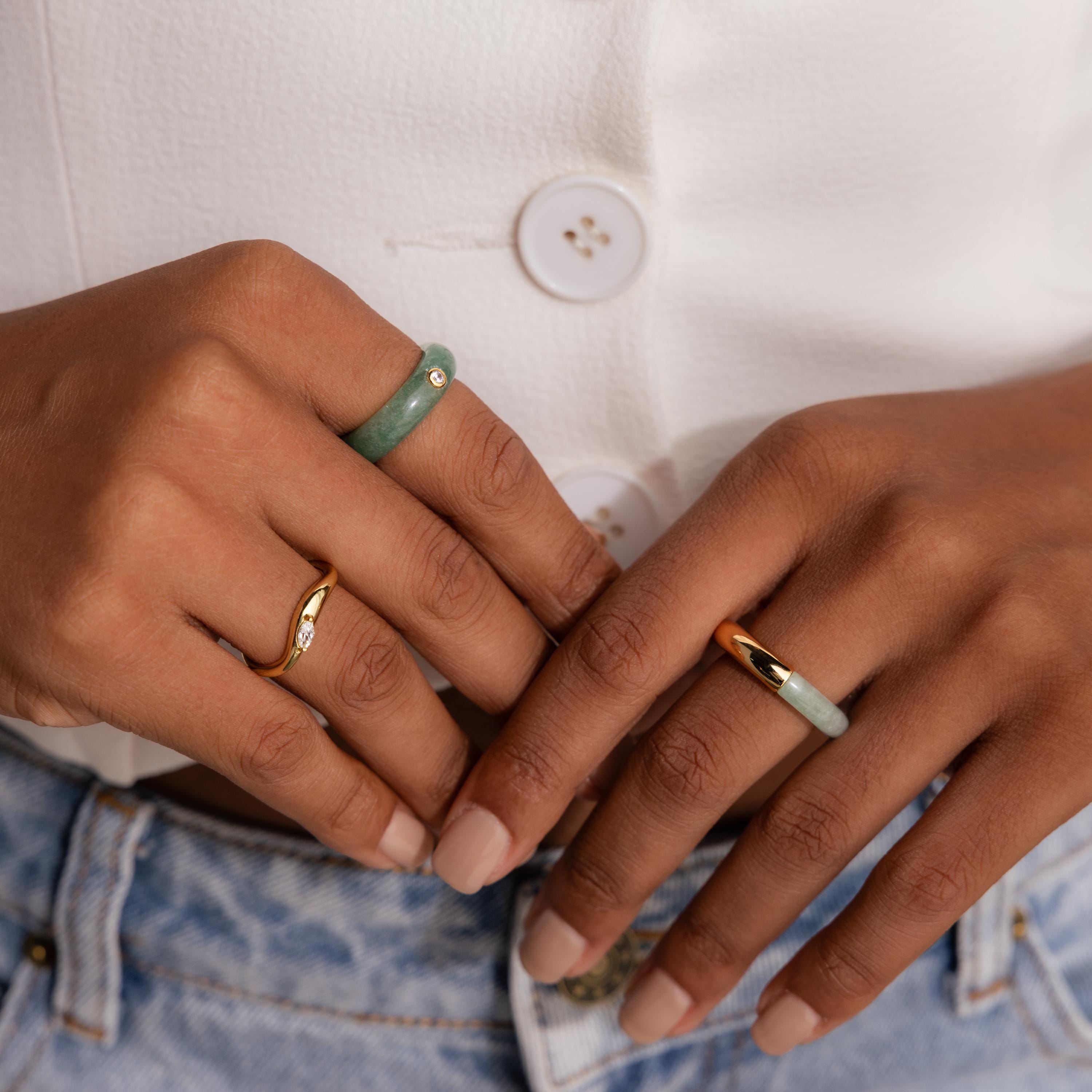 Close-up of hands wearing the Jade Diamond Ring with a gold bezel and green jade accents, styled with a white top and blue jeans.