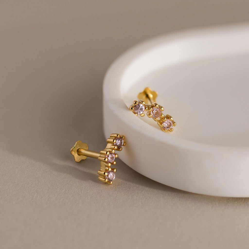Birthstone Cluster Flatback Studs featuring gold and small pink gemstones, perfect for stacking or wearing as delicate birthstone earrings, displayed on a round white dish.