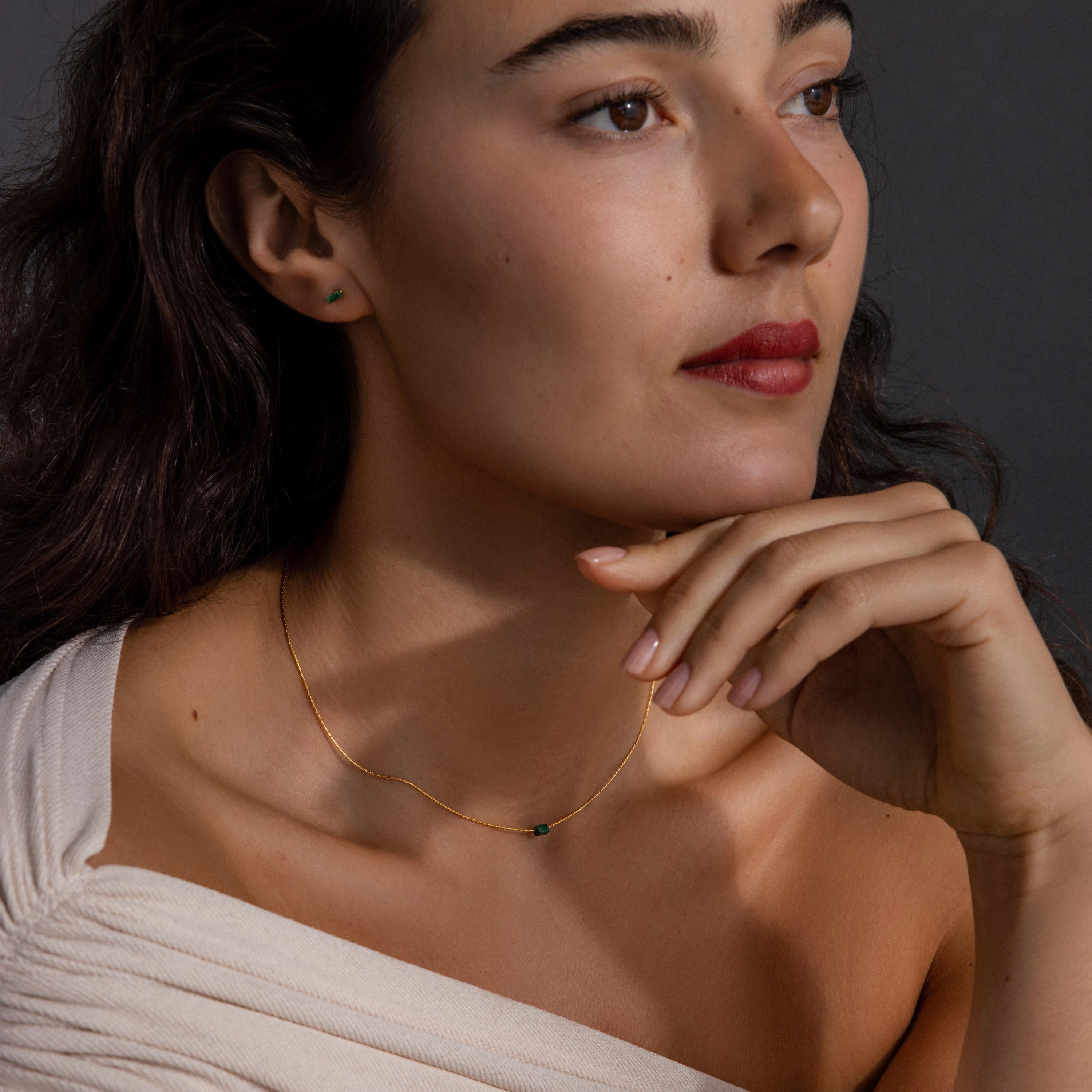 Woman with wavy dark hair gazes thoughtfully to the side, wearing the Jade Bar Jewelry Set in 18K Gold.