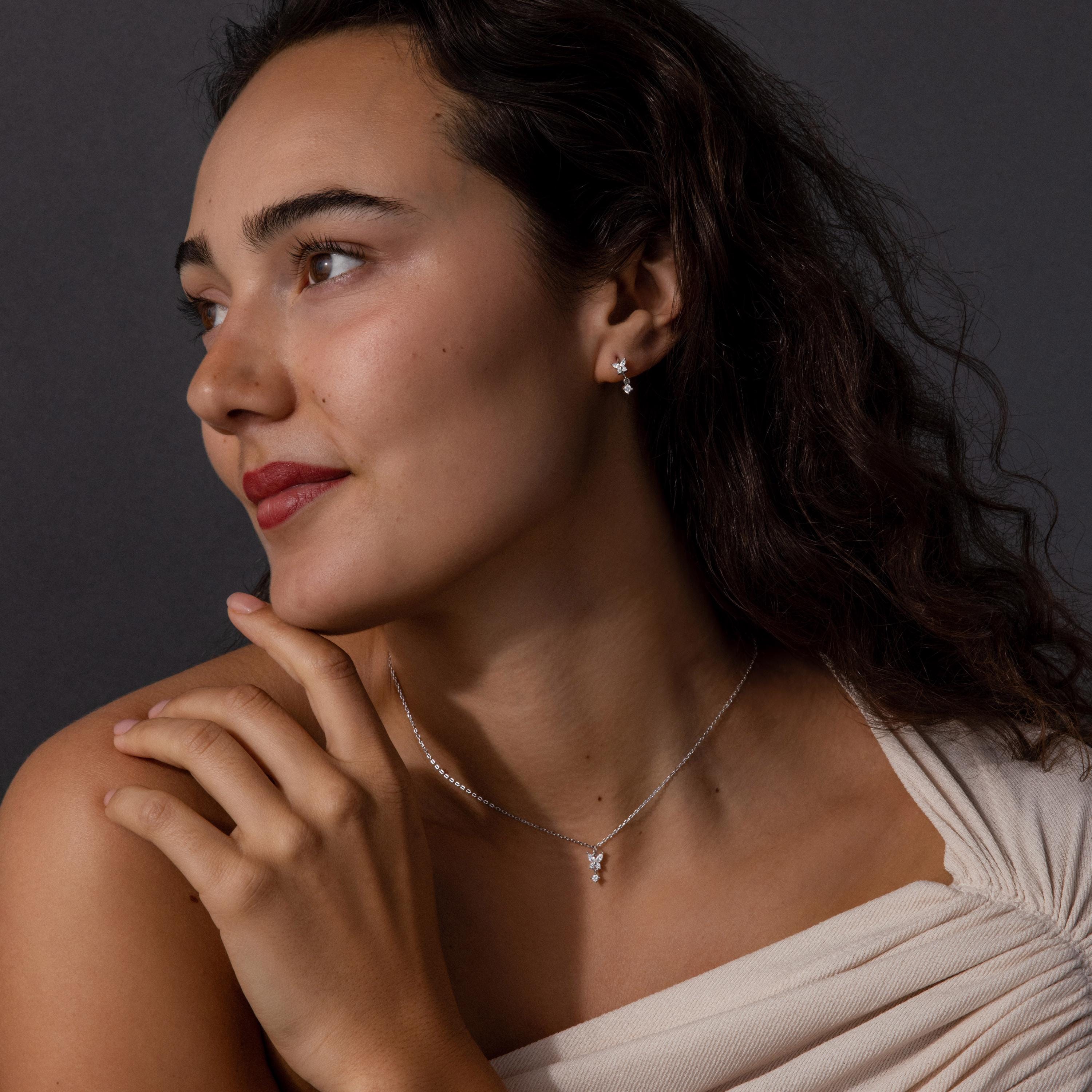 Woman with wavy hair wearing a cream top and the Diamond Butterfly Drop Jewelry Set, looking to the side.
