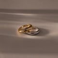 The Mixed Metal Dome Ring Set—featuring a gold and a silver ring side by side on a smooth surface with soft lighting—captures modern style and versatility, making it the perfect jewelry choice for any occasion.