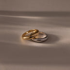 The Mixed Metal Dome Ring Set—featuring a gold and a silver ring side by side on a smooth surface with soft lighting—captures modern style and versatility, making it the perfect jewelry choice for any occasion.