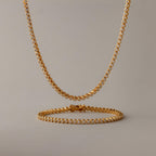 Diamond Bezel Tennis Necklace & Bracelet Set in 18K Gold, featuring round white stones, displayed on a plain beige background.