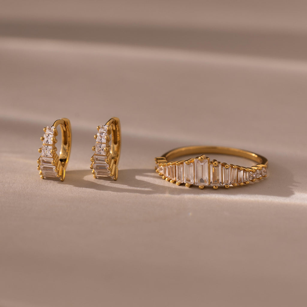 Art Deco Diamond Earrings & Ring Set in 18K Gold, featuring rectangular and round clear stones inspired by vintage jewelry, displayed on a beige surface.