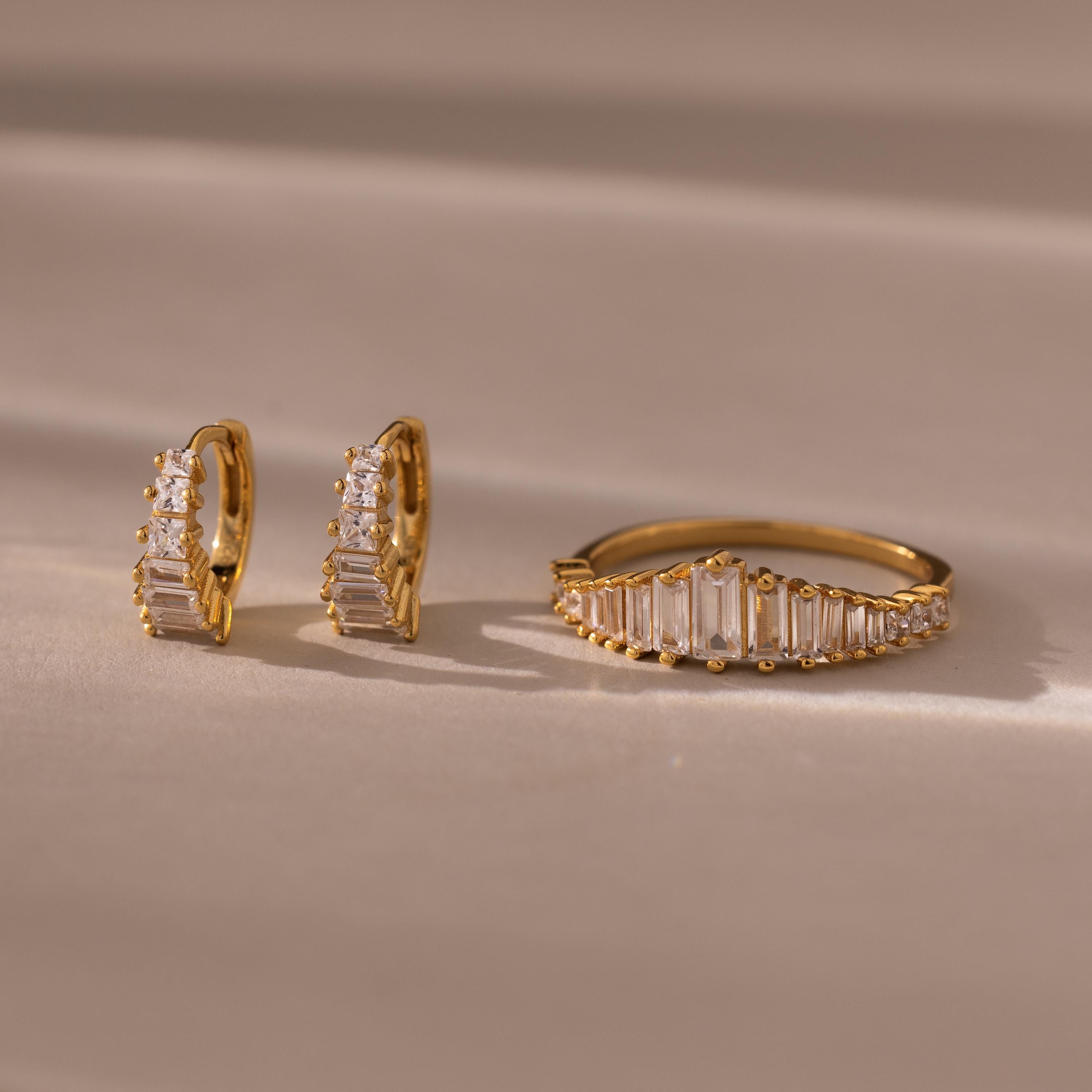 Art Deco Diamond Earrings & Ring Set in 18K Gold, featuring rectangular and round clear stones inspired by vintage jewelry, displayed on a beige surface.